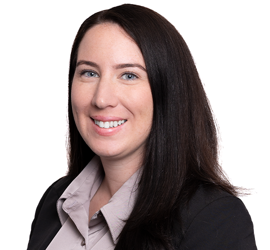 A professional woman with long dark hair wearing a gray blouse and black blazer, smiling at the camera against a white background.